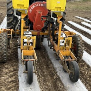 Tractor planting seeds in prepared soil rows.